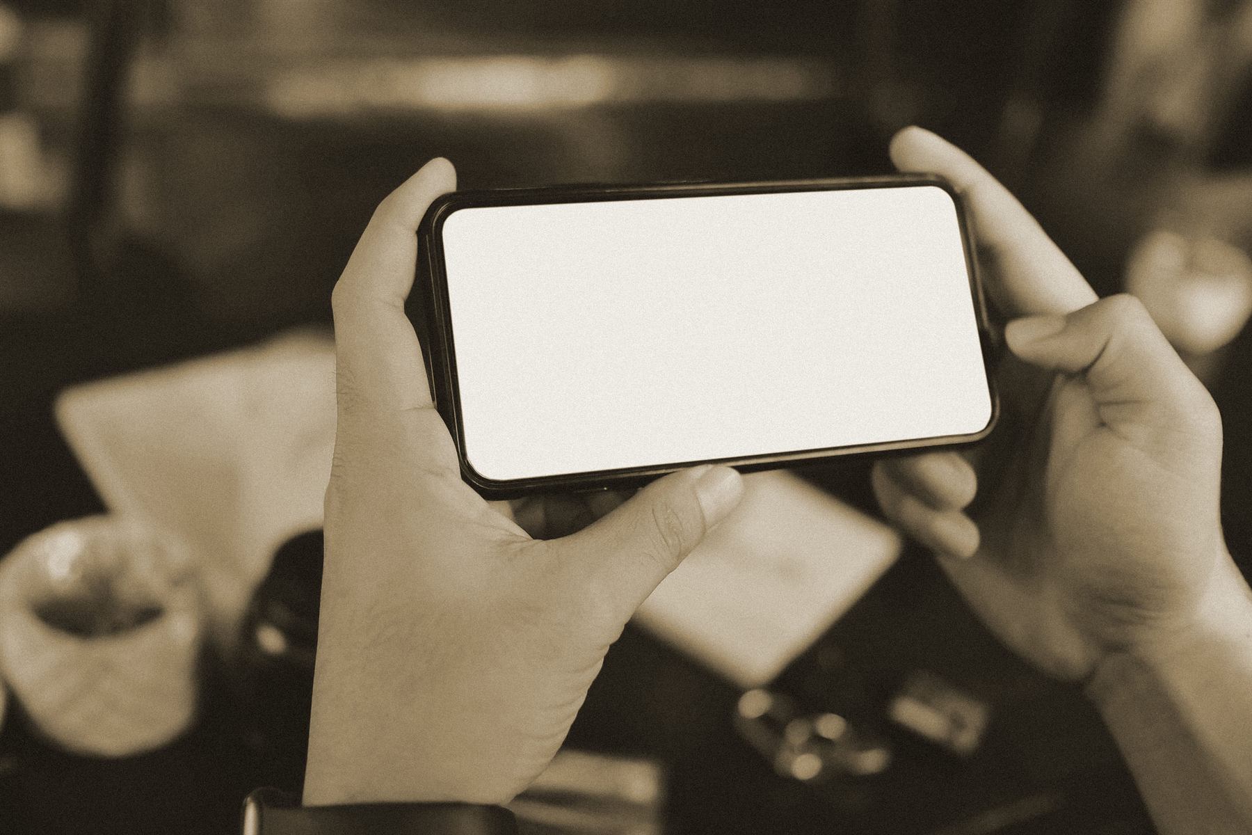Dłonie trzymające smartfon w poziomie